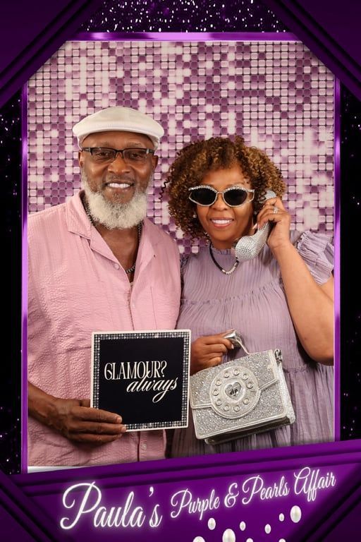 Man and woman smiling at Paula’s Purple and Pearls celebration backdrop