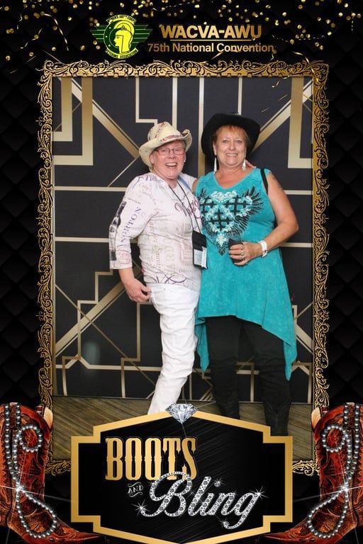 Two women posing at a Boots & Bling event backdrop, one in white and one in teal.