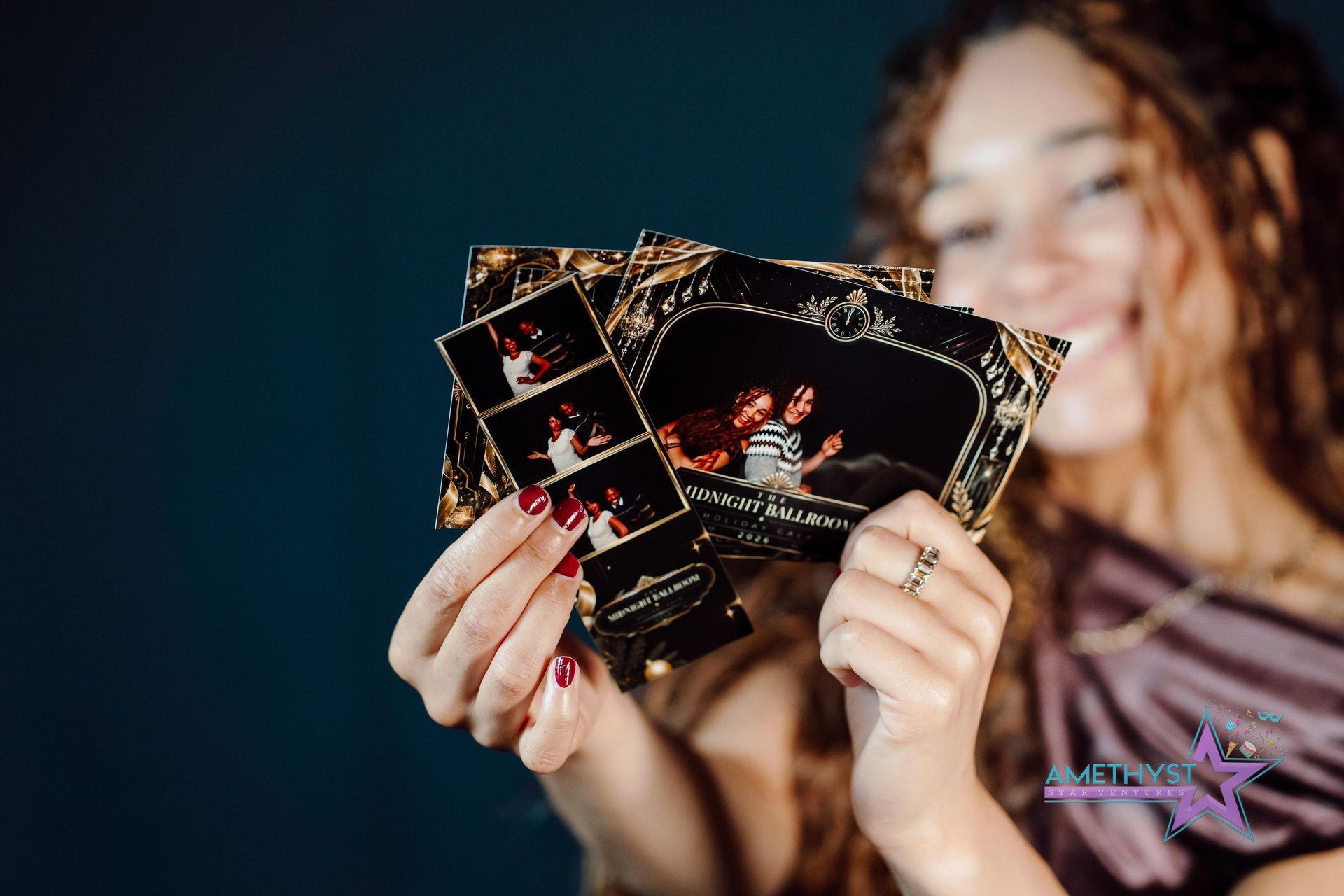 Person holding three glossy black photo cards against a dark background, smiling out of focus.