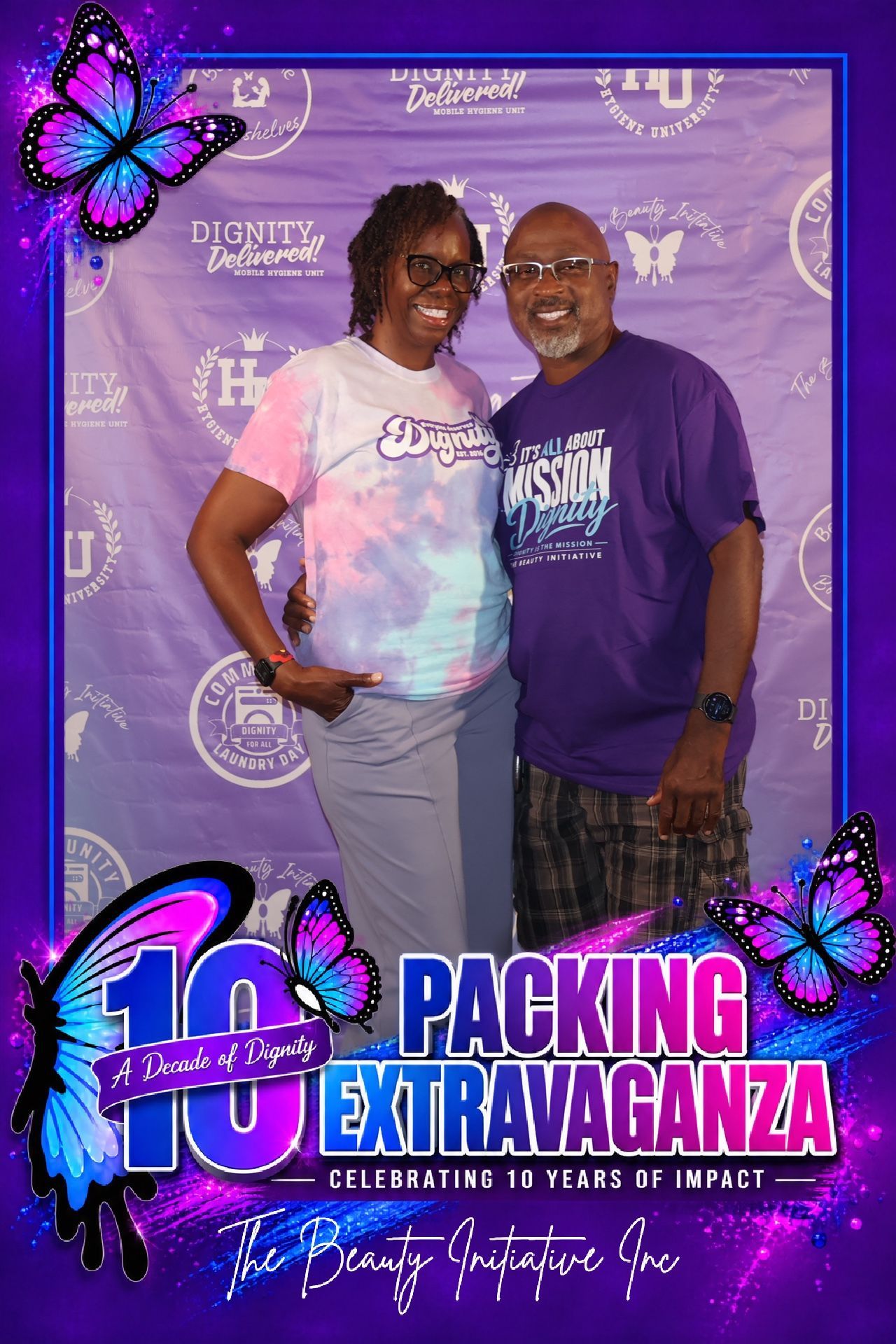 Two adult supporters posing in front of Beauty Initiative’s A Decade of Dignity event backdrop