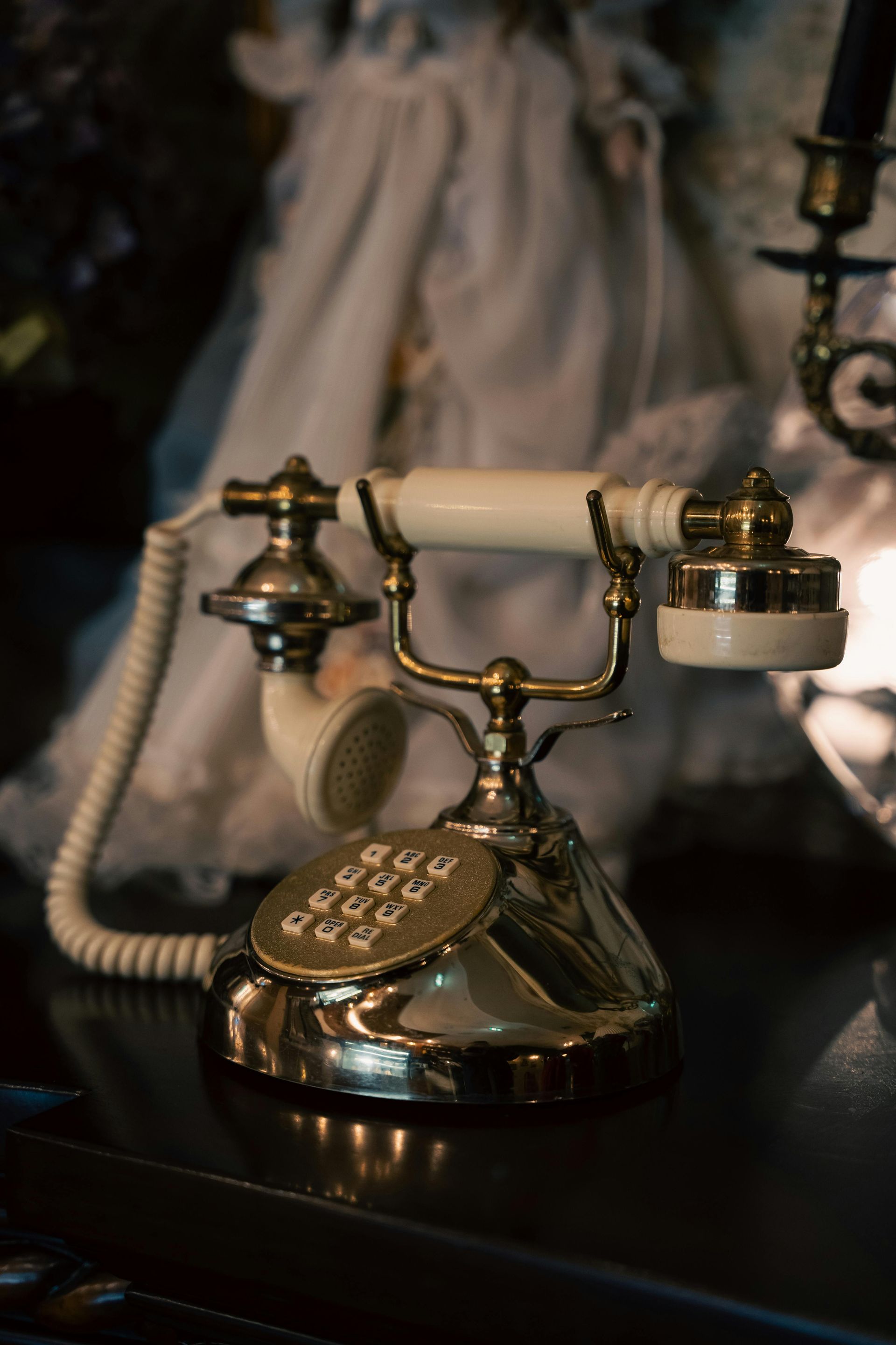 Brass rotary phone on a dark table, with a blurred figure in the background.