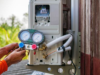 Technician adjusting pressure gauges on an outdoor electrical meter box