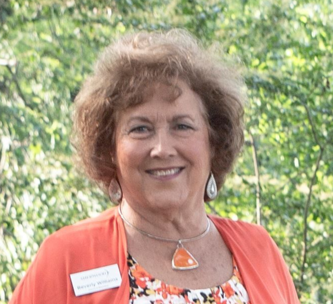 A smiling person wearing an orange cardigan