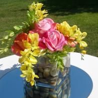 Colorful flower bouquet in a glass vase on a white table outdoors