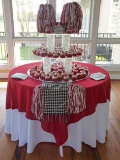 Red and white dessert display table with layered trays and tassel decorations in a bright room