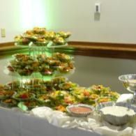 Buffet table with tiered trays of hors d’oeuvres, salads, and serving dishes in a banquet room