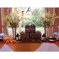Table of assorted gifts and floral arrangements in a decorated indoor event setting