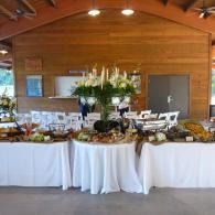 Buffet table with white tablecloths and floral centerpiece in a wooden banquet hall