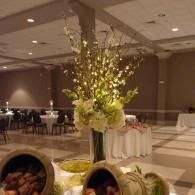 Elegant banquet hall with tall floral centerpieces and set tables under warm lighting