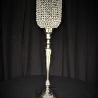 Decorative silver floor lamp with textured shade against a black curtain backdrop
