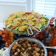 Buffet table with salad and a bowl of croutons, decorated with autumn leaves