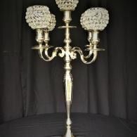 Ornate silver candelabra with five candle cups against a black draped background