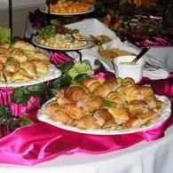 Assorted pastries on platters at a buffet table with pink and white table linens