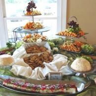 Buffet table with assorted breads, pastries, fruit, and desserts arranged on tiered trays