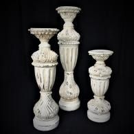Three ornate white carved candleholders on a black background