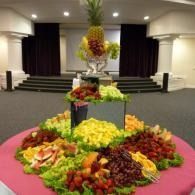 Fruit display arranged in tiers on a pink tablecloth in a banquet hall