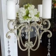 White floral centerpiece on an ornate cream candelabra with hanging crystals and candles