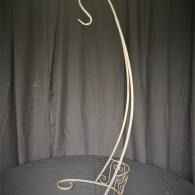 White metal wall hook with ornate swirls against a dark curtain background