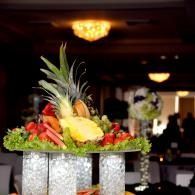 Fruit and vegetable centerpiece on a banquet table with pineapple, strawberries, and leafy greens
