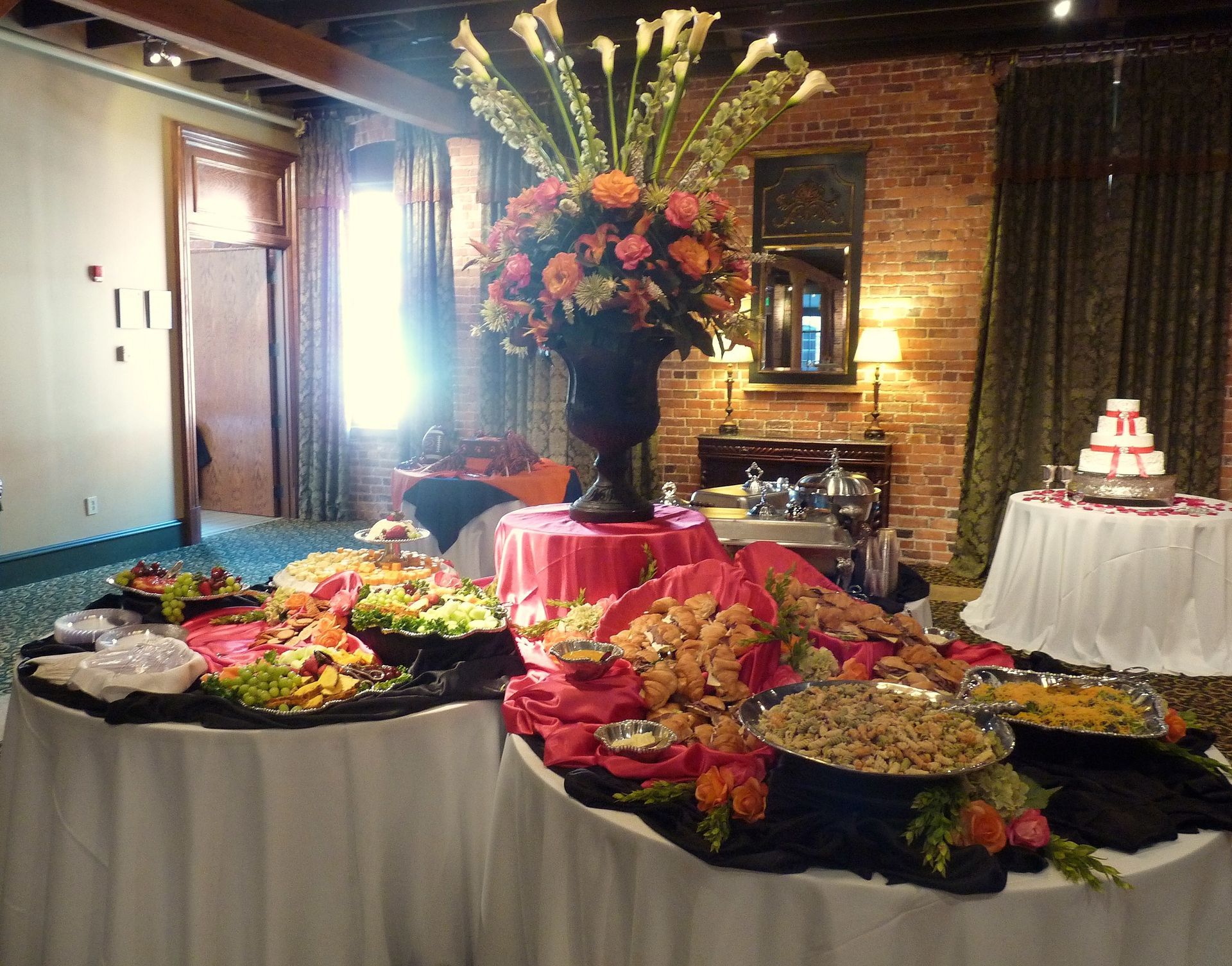 Buffet table with colorful floral arrangements in a brick-walled banquet room