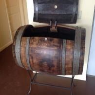 Wooden barrel-shaped sink with metal stand in a bathroom hallway