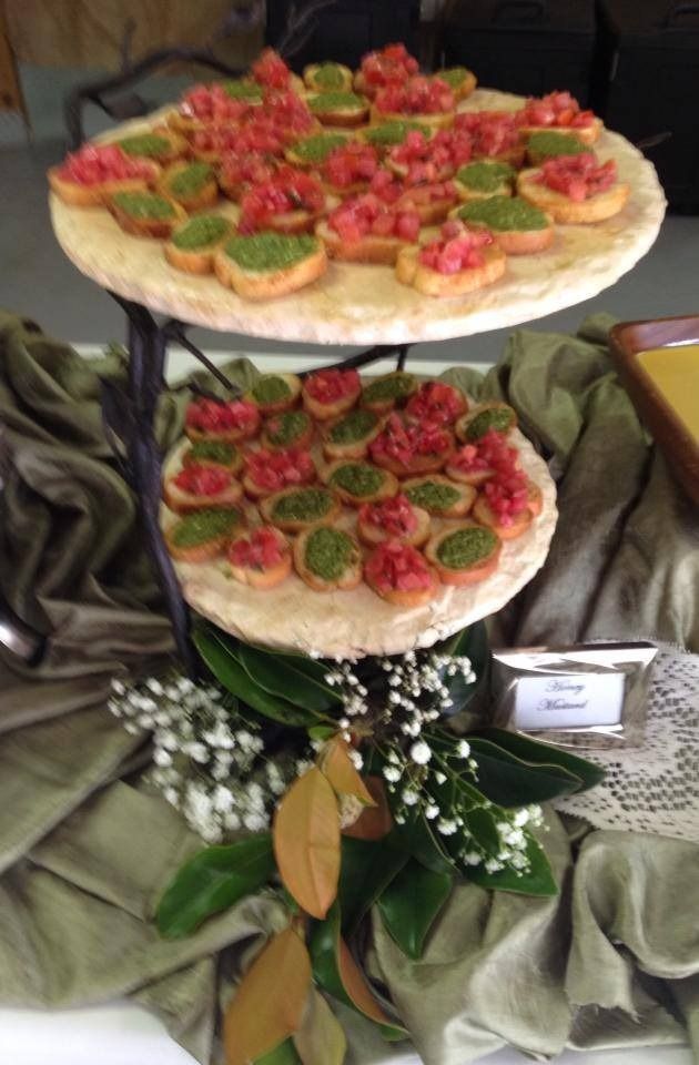 Tiered appetizer display with bruschetta-style canapés and decorative greenery on a table.