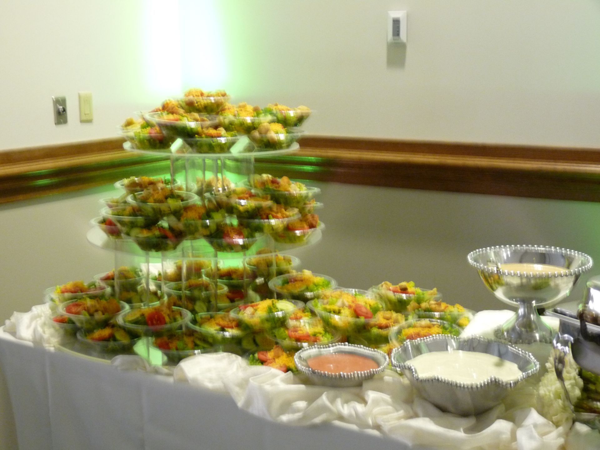 Tiered trays of fruit and desserts on a buffet table with white and silver serving dishes
