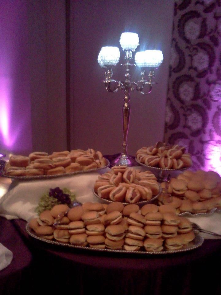 Dessert table with trays of pastries and cookies under a lit candelabra