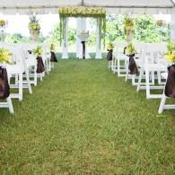Outdoor wedding aisle with white chairs and hanging floral decorations under a tent