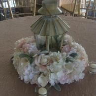 Floral centerpiece with a lantern on a round table in a banquet hall
