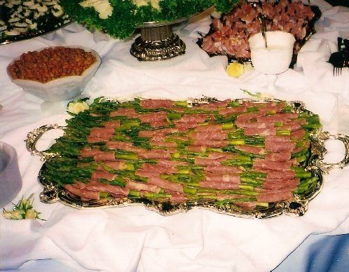 Platter of sliced roast beef garnished with parsley, surrounded by side dishes on a white tablecloth