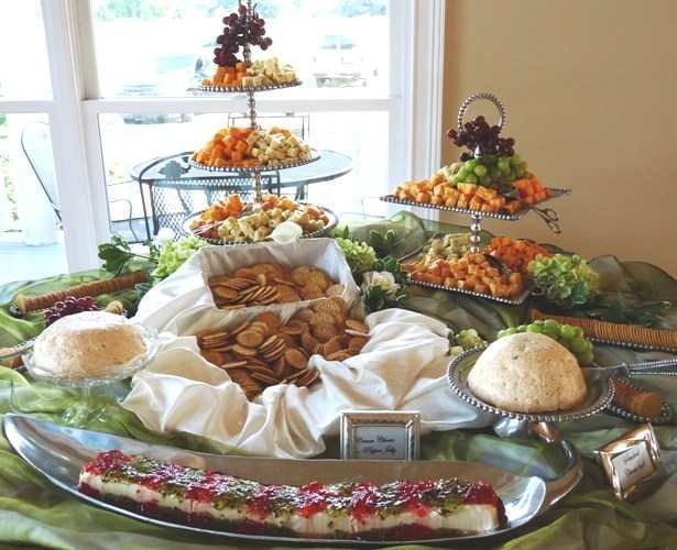 Elegant buffet table with tiered trays of fruit, pastries, and rice dishes by a bright window