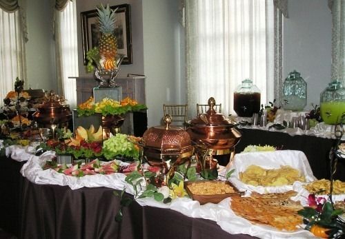 Buffet table with assorted dishes, fruit, and serving pots in a formal dining room