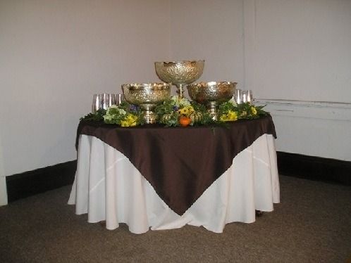 Decorated banquet table with gold bowls, glasses, and flowers in a corner room