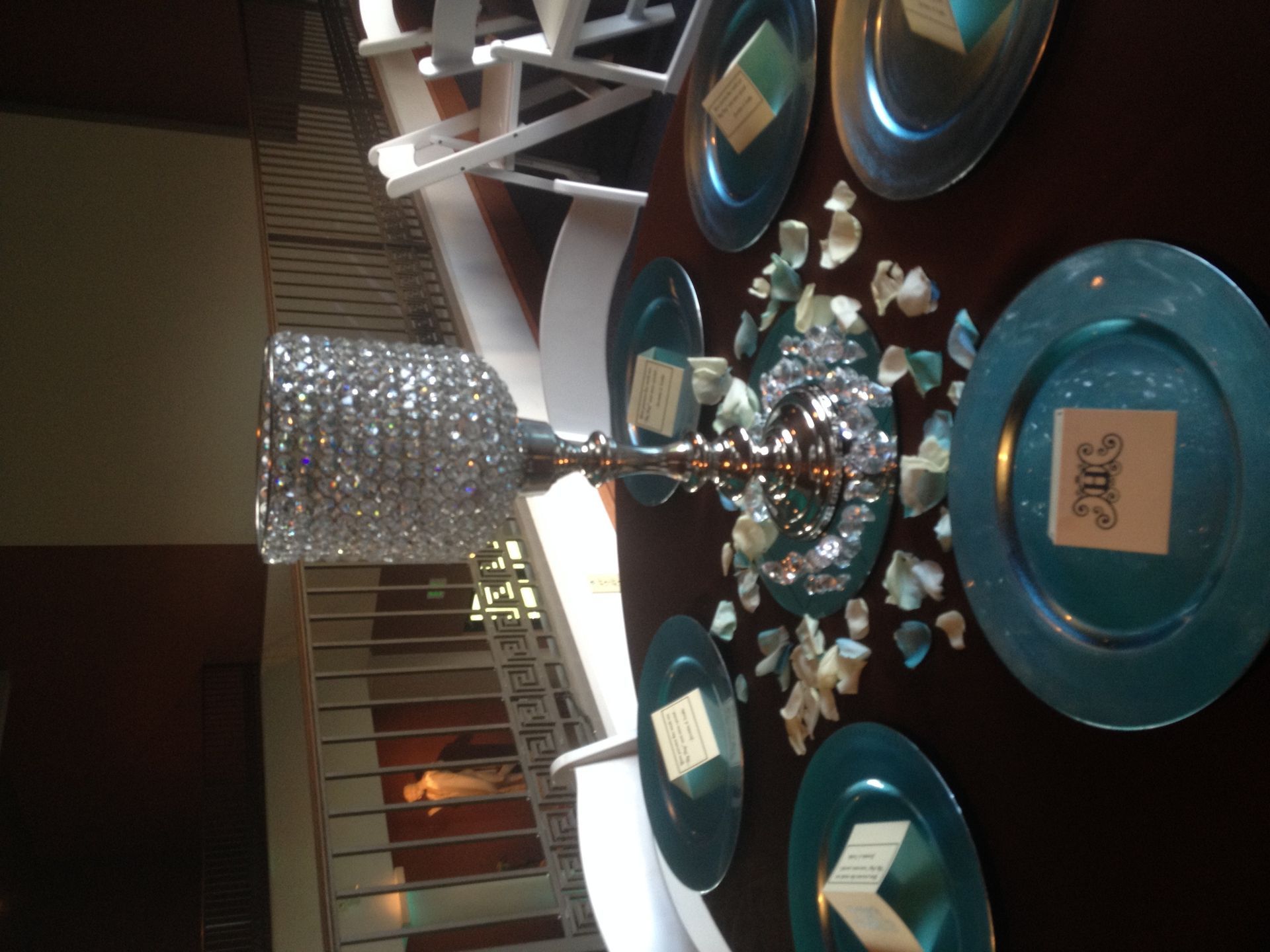 Dining table with teal plates, mirrored centerpiece, and silver lamp in a warmly lit room