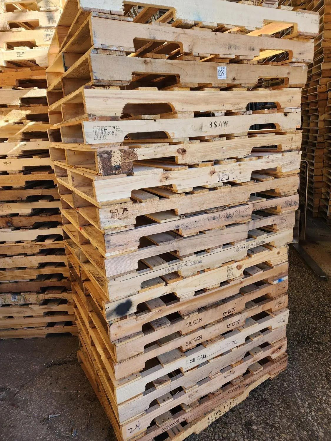A stack of wooden pallets sitting on top of each other on the ground.