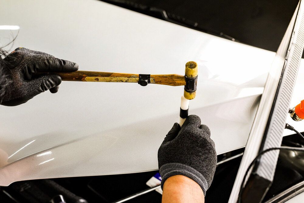 A Person Is Working On A Car With A Hammer — K & D Auto Repair in Cardiff, NSW