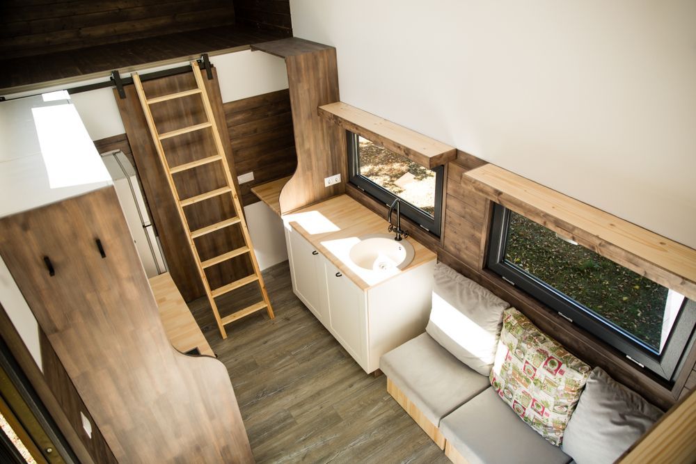Interior View of a Tiny House With a Kitchen, Sofa, and Loft Accessed by a Ladder — Darren's Caravan Repairs in Warners Bay, NSW