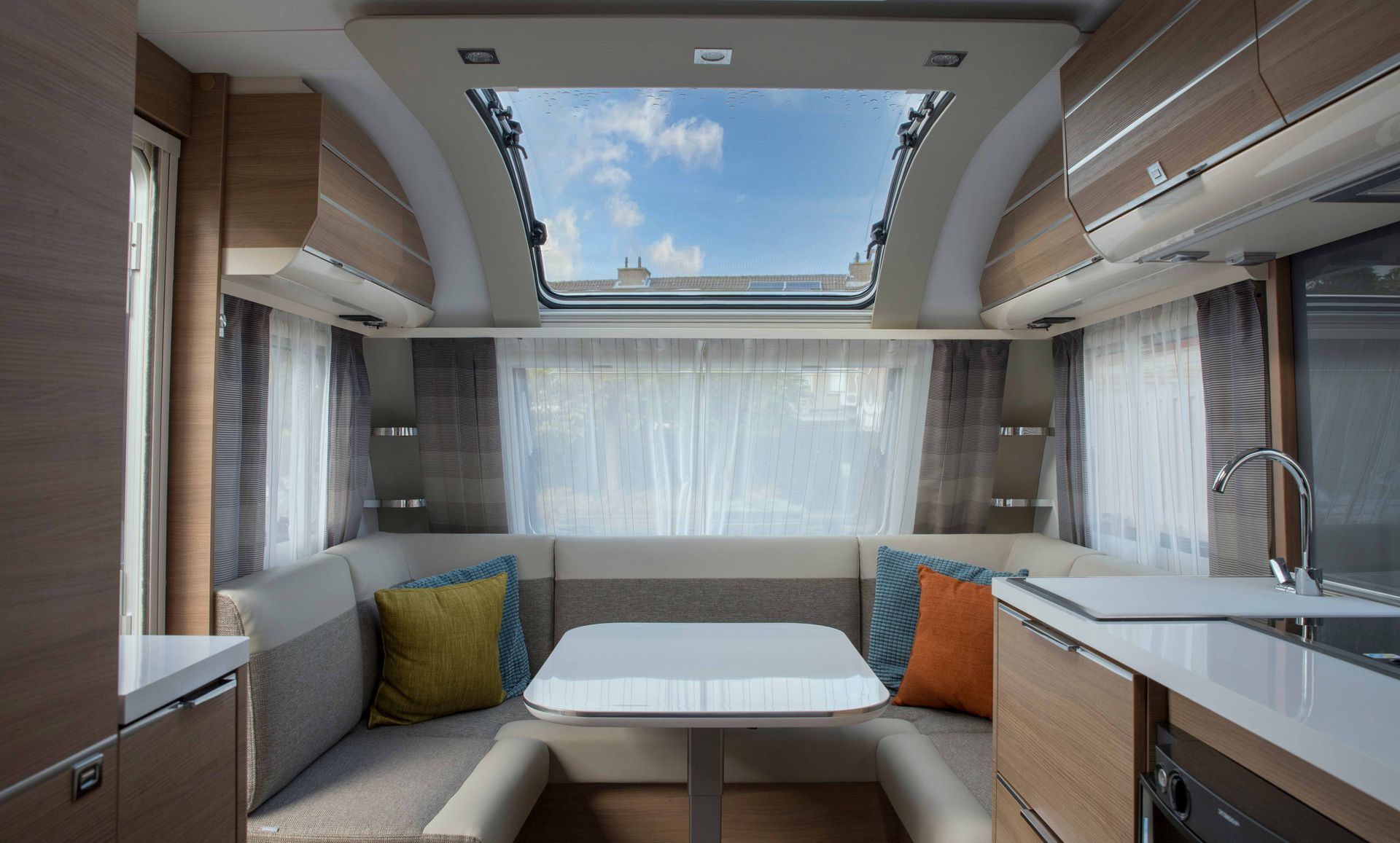 Interior of a Caravan, Featuring a Seating Area, Table, Kitchen With Sink and Window With Sky View — Darren's Caravan Repairs in Lake Macquarie, NSW
