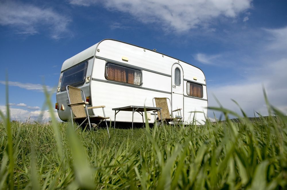 White Caravan on a Green Grassy Field Under a Blue Sky — Darren's Caravan Repairs in Warners Bay, NSW