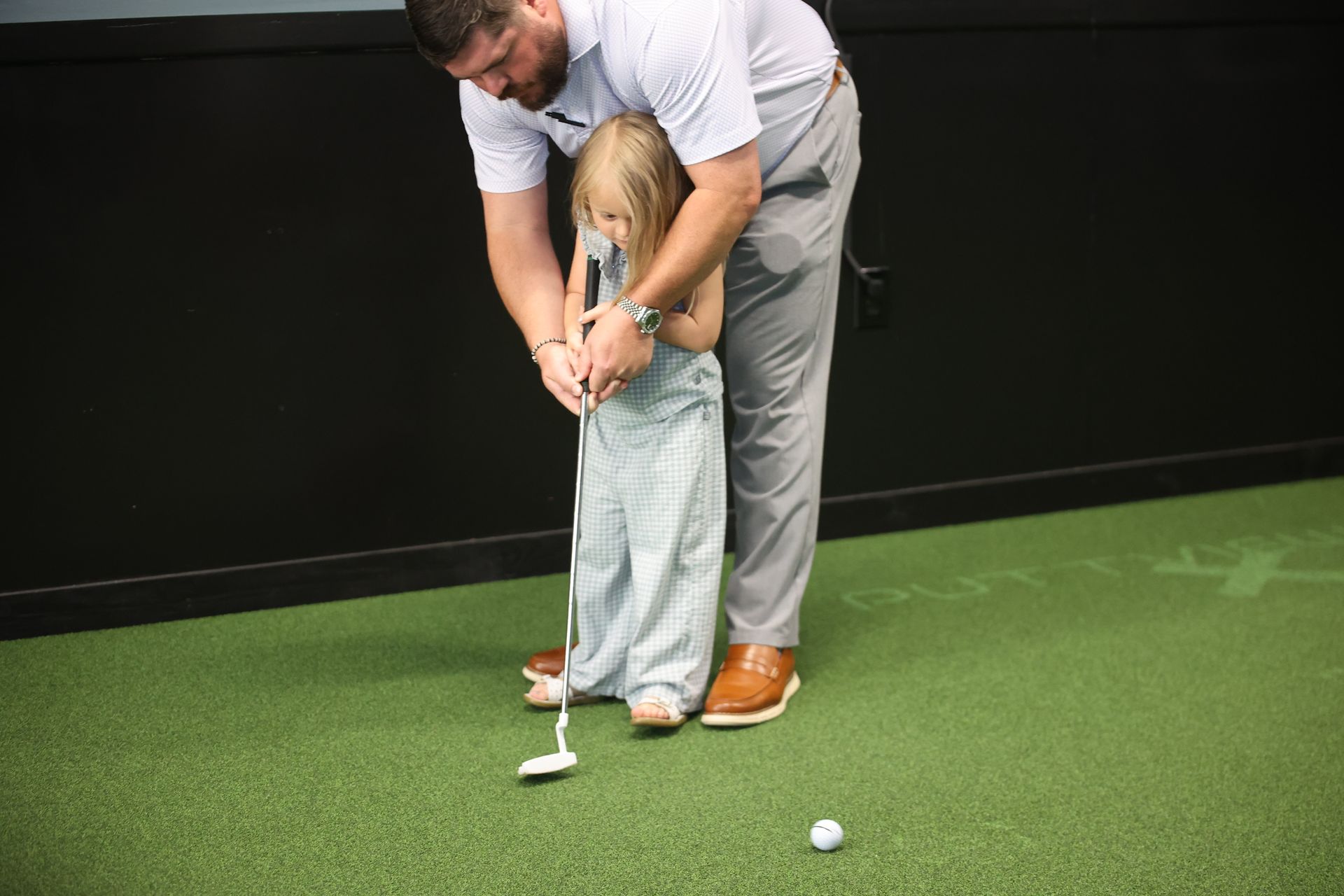 A father teaching his daughter to golf at Tee It Up in downtown Texarkana