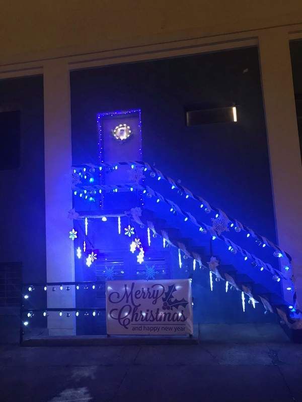 Exterior building decorated with blue Christmas lights, icicles, and a 