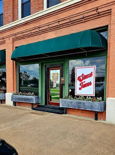 A brick building with a green awning. The shop's windows display a