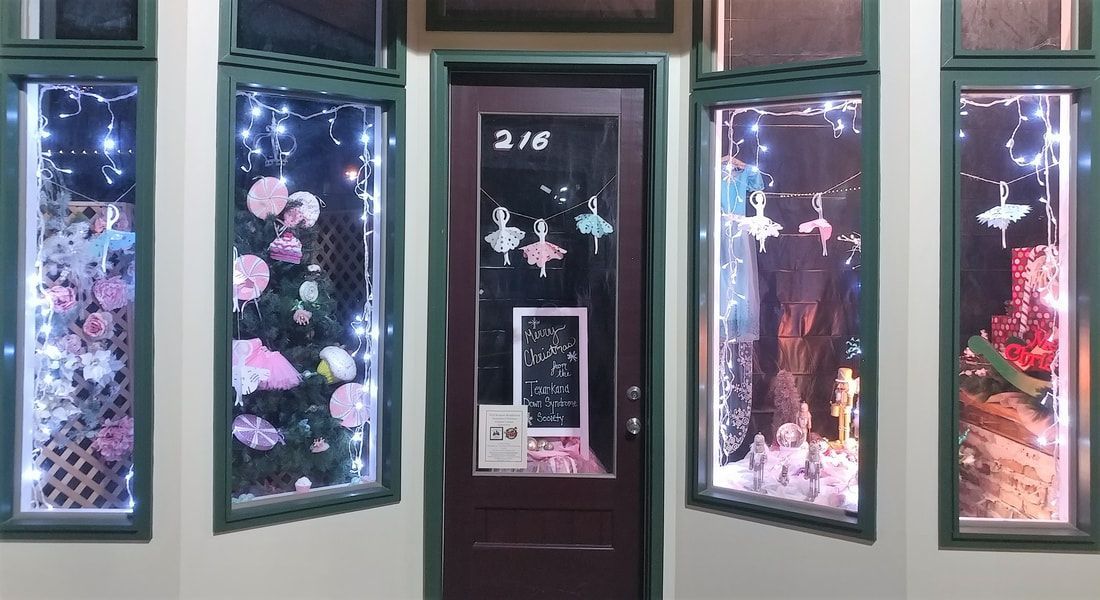 Shopfront with decorated windows and door, featuring lights, flowers, and decorations.