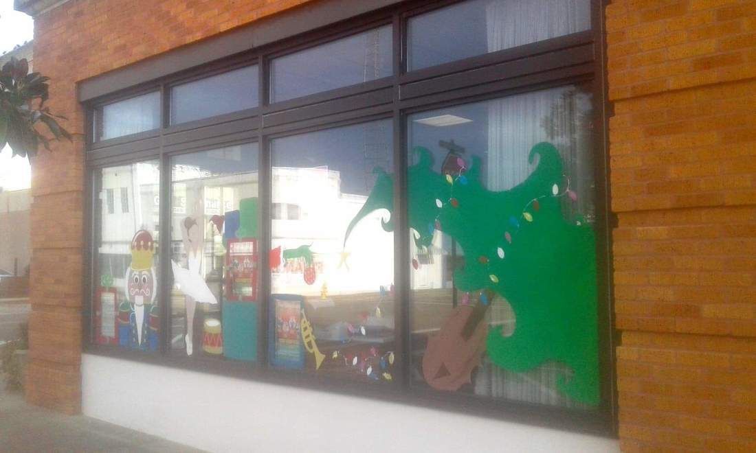 Storefront window display with colorful cutouts and objects against a reflective glass background.