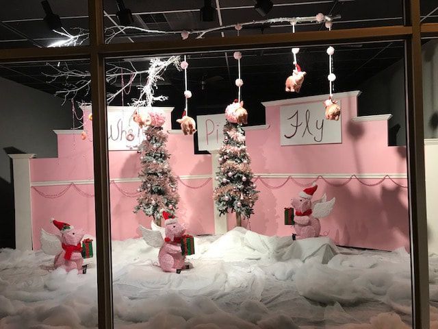 Christmas window display with pigs wearing Santa hats and angel wings, 