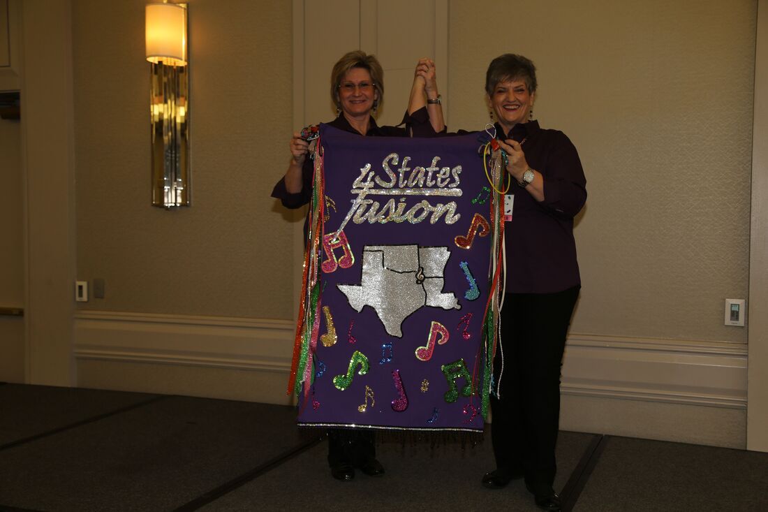 Two women holding up a purple banner that reads 