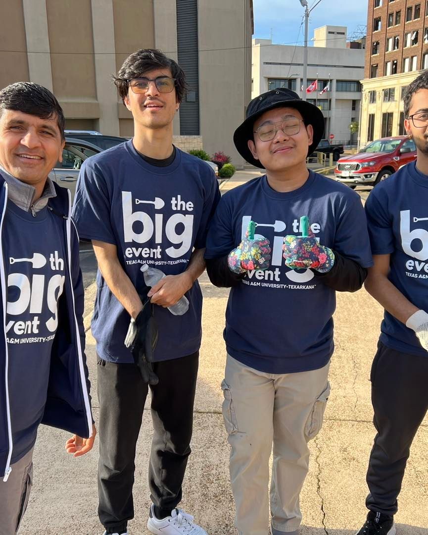 Four people in matching blue shirts standing outside; 