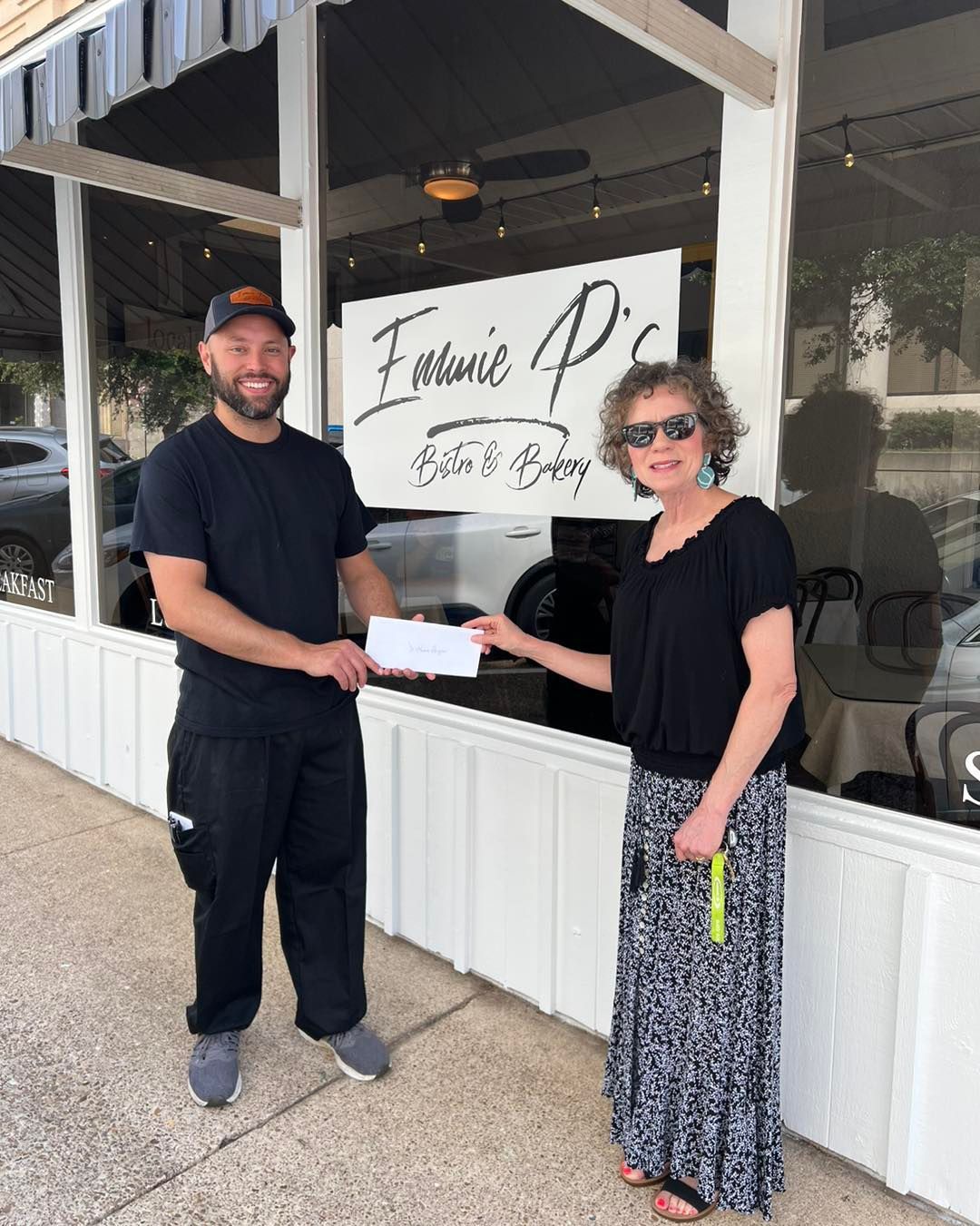 Man in black shirt receives a check from a woman in front of 