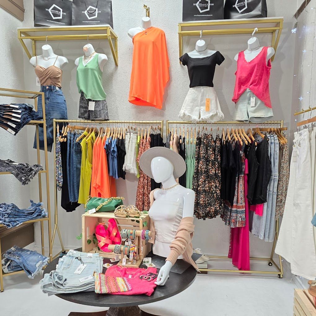 Clothing store display with racks of clothing, mannequins wearing tops and shorts.